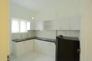 a kitchen with white cabinets and a black refrigerator at Yelza Hotel and Residence in Alwaye