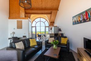 a living room with black leather furniture and a table at Grimaud 141 - Kustpark Village Scaldia in Hoofdplaat
