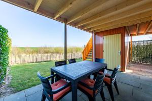 a dining table and chairs on a patio at Grimaud 141 - Kustpark Village Scaldia in Hoofdplaat
