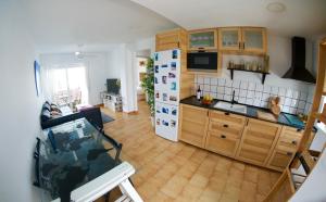 a kitchen with wooden cabinets and a white refrigerator at "soñaC soL" in Los Caños de Meca