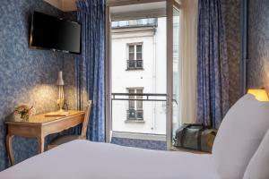 a bedroom with a bed and a desk and a window at Hôtel Baudelaire Opéra in Paris +39 photos