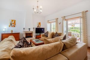 uma sala de estar com um sofá e uma televisão em Stunning T3 Vila dos Príncipes em Casal da Lagoa Seca