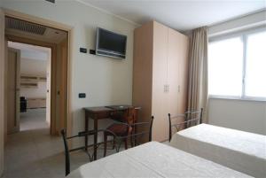 Residence & Suites Solaf في Bonate di Sopra: غرفة نوم بسريرين ومكتب وتلفزيون