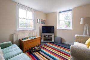 a living room with a couch and a tv at Mere Cottage - Aldeburgh Coastal Cottages in Thorpeness