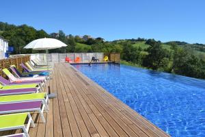 a swimming pool with chairs and an umbrella on a wooden deck at Résidence L'Oustal Del Carlat in Carla-Bayle
