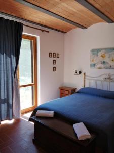 Un dormitorio con una cama azul y una ventana en Il Casale di Luna, en Saturnia