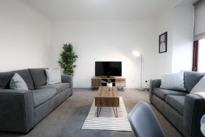 a living room with two couches and a tv at Sonas Apartment Greenock in Greenock