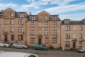 un gran edificio de ladrillo con coches estacionados frente a él en Sonas Apartment Greenock, en Greenock