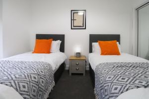 2 camas con almohadas de color naranja en una habitación en Sonas Apartment Greenock, en Greenock