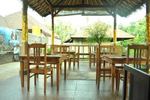 a group of wooden tables and chairs in a restaurant at Bali Gecko Homestay in Pemuteran