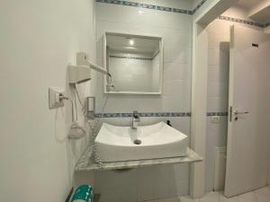 ein weißes Badezimmer mit einem Waschbecken und einem Spiegel in der Unterkunft Ma&Mi Guest House in Cefalú
