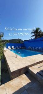 a swimming pool with a stone bench next to a swimming pool at Residencial Rosi in Caraguatatuba