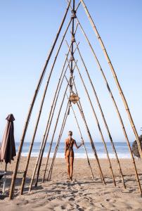 una mujer caminando a través de un marco en la playa en Baxar en Pie de la Cuesta