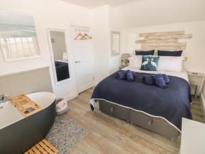a bedroom with a large bed and a bath tub at 2 Salt Cottage in Swansea