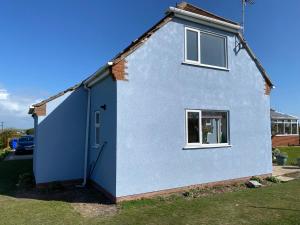 una casa azul con una ventana y una puerta en Puffin Place en Flamborough