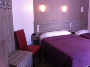 a hotel room with two beds and a red chair at Grand Hôtel Magenta in Paris