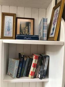 a book shelf filled with books and framed pictures at Maggies Cottage in Manorhamilton