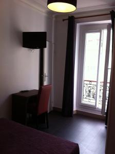 a room with a bed and a window with a desk at Grand Hôtel Magenta in Paris