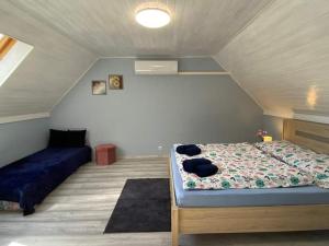 a bedroom with a bed and a couch in a attic at Helena apartman in Cserszegtomaj