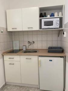 a kitchen with white cabinets and a microwave at Helena apartman in Cserszegtomaj