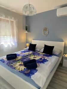 uma cama grande com um edredão azul e branco em Helena apartman em Cserszegtomaj