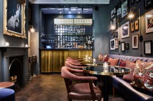 a bar with couches and tables and a fireplace at The Tophams Hotel in London