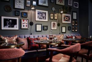 a bar with a couch and tables and pictures on the wall at The Tophams Hotel in London