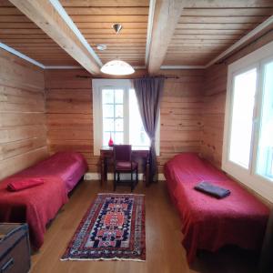 two beds in a room with wooden walls and windows at Rysseli in Kiuruvesi