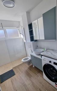 biała łazienka z umywalką i pralką w obiekcie Lily Central Apartment with free parking w mieście Târgu Mureş