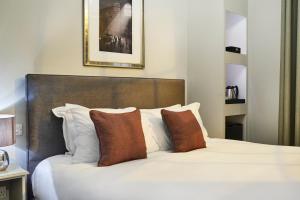 a bedroom with a white bed with brown pillows at The Tophams Hotel in London