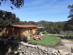 a small house with chairs and a stone wall at Eco Lodge nella natura "La Grande Quercia" in Calangianus