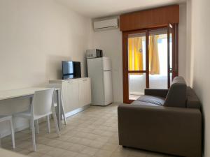 Una sala de estar con un sofá, una mesa y un refrigerador. en Solemare Federica, en Lignano Sabbiadoro
