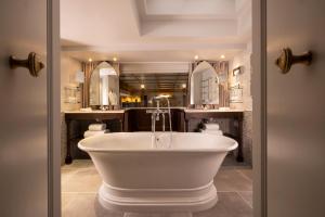 La salle de bains est pourvue d'une baignoire blanche et de miroirs. dans l'établissement Maison Cardinal Furstemberg, à Paris