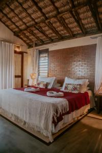 a large bed in a room with a brick wall at Pousada Café Zapata in Amontada