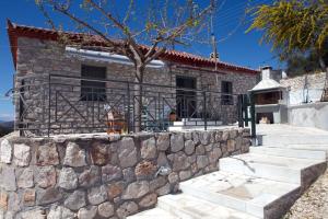 a stone house with a stone wall and a tree at Traditional House Kakopetra in Nafplio