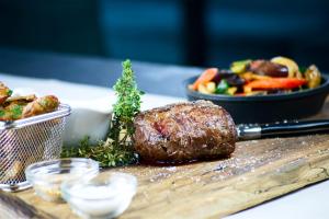 a table with a steak and a plate of food at Hotel Das Zeit in Lenzing