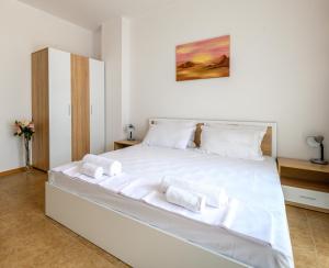 una camera da letto con un letto bianco e asciugamani di Robinson Beach Apartments a Elenite