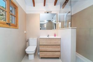 een badkamer met een toilet, een wastafel en een spiegel bij Se Taulera in Fornalutx
