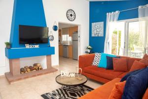 ein Wohnzimmer mit einem orangenen Sofa und einem Kamin in der Unterkunft Villa Salieri: Coral Bay villa with private pool in Peyia