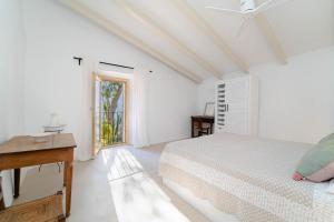 a white bedroom with a bed and a window at Se Taulera in Fornalutx