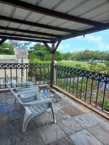 a patio with two chairs and a view of a golf course at AVA BEACH HOUSE in Blue Bay