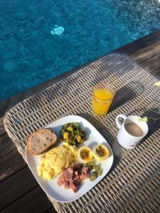 a plate of eggs and ham and toast next to a pool at ZANNAMALAKA 2 F1 POUR UN GROUPE DE 4 Avec Piscine in Le Moule