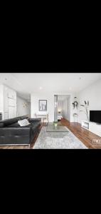 a living room with a black couch and a television at Lovely apartment in Melbourne +9 photos