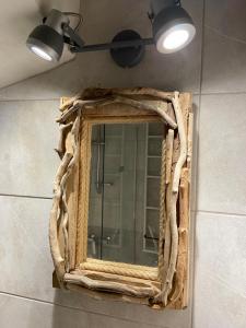 a mirror with a wooden frame on a wall at Pepper Tree in Egina