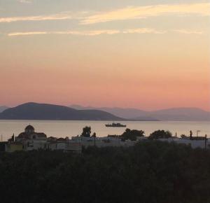 a view of a city and the water at sunset at Pepper Tree in Egina