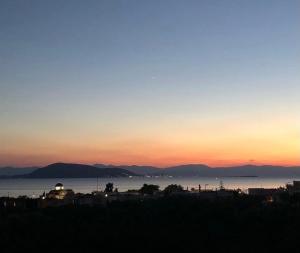 a sunset over a body of water with mountains in the background at Pepper Tree in Egina
