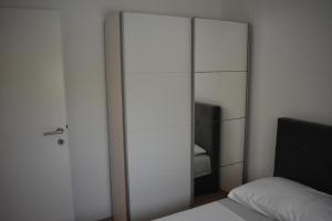 a bedroom with a glass closet with a bed at Apartman DODO in Zadar