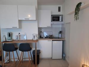 una pequeña cocina con encimera y taburetes. en Le levant - avec loggia - à 20m de la plage, en Courseulles-sur-Mer 15 fotos más