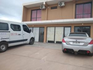 a white van and a silver car parked in front of a building at Norte Alojamiento in Belén