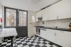 a kitchen with white cabinets and a checkered floor at Voorstraat-Straatzicht Boven in Dordrecht